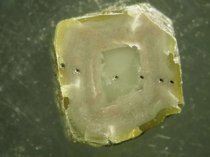 Slice of South African diamond with inclusion-rich zones and laser ablation pits from microanalysis