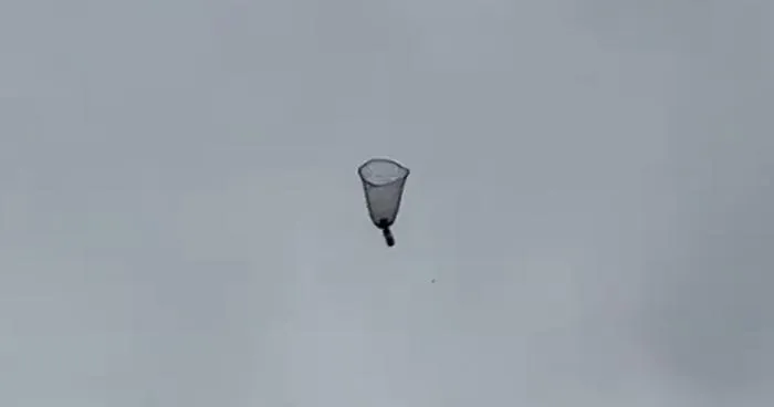 In free fall, the parachute takes the shape of an upside-down bell, slowing the descent of the weight attached to its centre.
