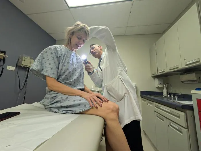 Dr. Pedram Gerami examines the skin of patient and melanoma survivor Heidi Tarr