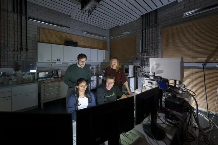 Researchers watching microscope screen