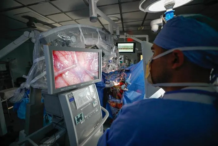 Taylor Furst, MD, observes a brain mapping procedure in progress at the University of Rochester’s Strong Memorial Hospital.