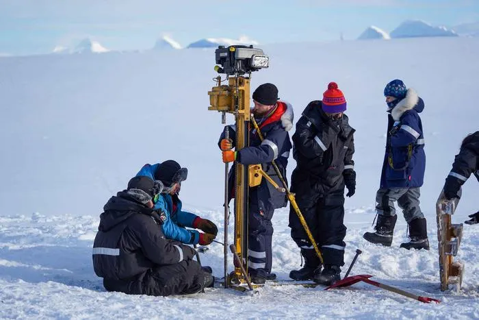 Field team drilling to extract soil and permafrost samples from the tundra in Svalbard, during winter.