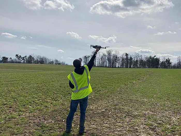 researcher launches a drone in a farm field