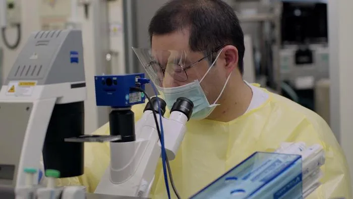 Photo of Peng Zhou at microscope