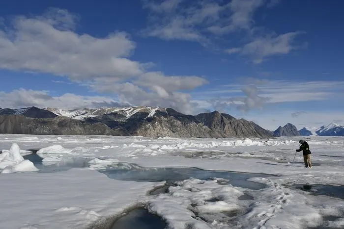 Silas Pijamini checking the ice before taking measurements of the water beneath it.