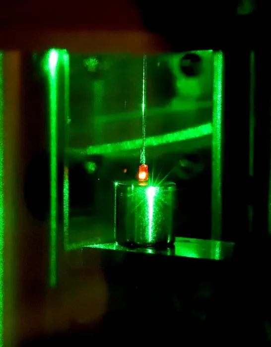 Photo of suspended diamond with nitrogen-vacancy centers illuminated by green laser